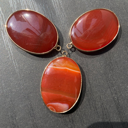 Handgeschliffener ovaler Naturstein Anhänger aus rotem Achat mit goldfarbener Fassung für DIY Schmuckherstellung und Boho Halsketten