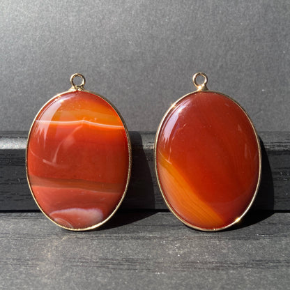 Handgeschliffener ovaler Naturstein Anhänger aus rotem Achat mit goldfarbener Fassung für DIY Schmuckherstellung und Boho Halsketten