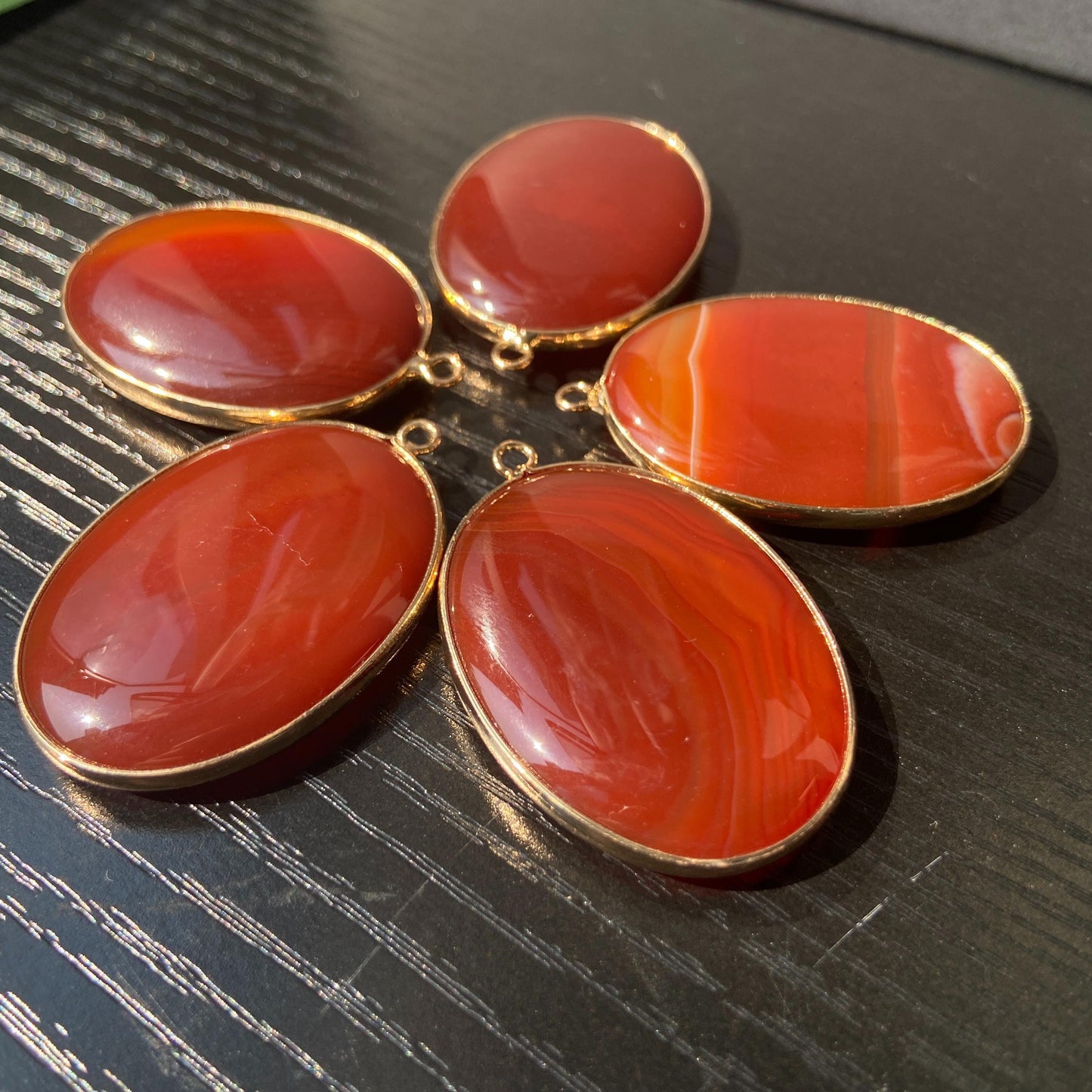 Handgeschliffener ovaler Naturstein Anhänger aus rotem Achat mit goldfarbener Fassung für DIY Schmuckherstellung und Boho Halsketten