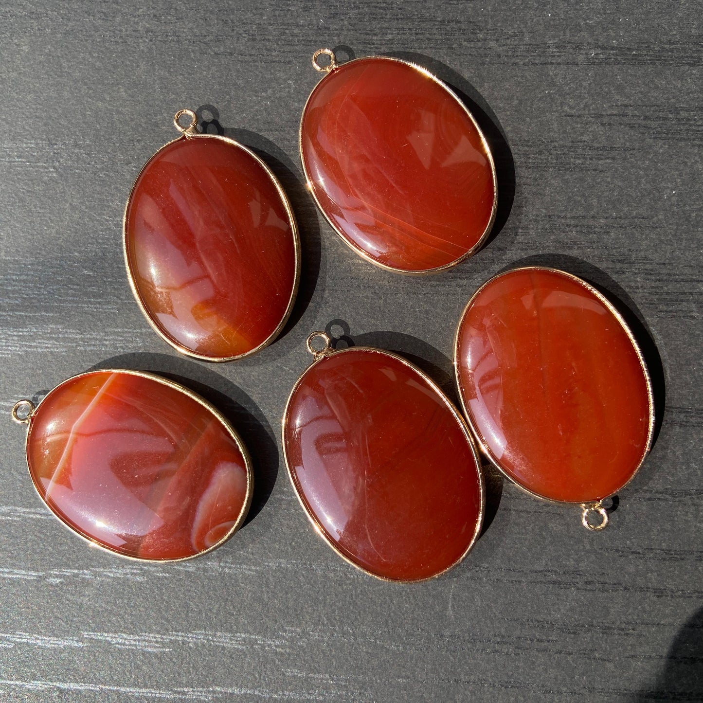 Handgeschliffener ovaler Naturstein Anhänger aus rotem Achat mit goldfarbener Fassung für DIY Schmuckherstellung und Boho Halsketten