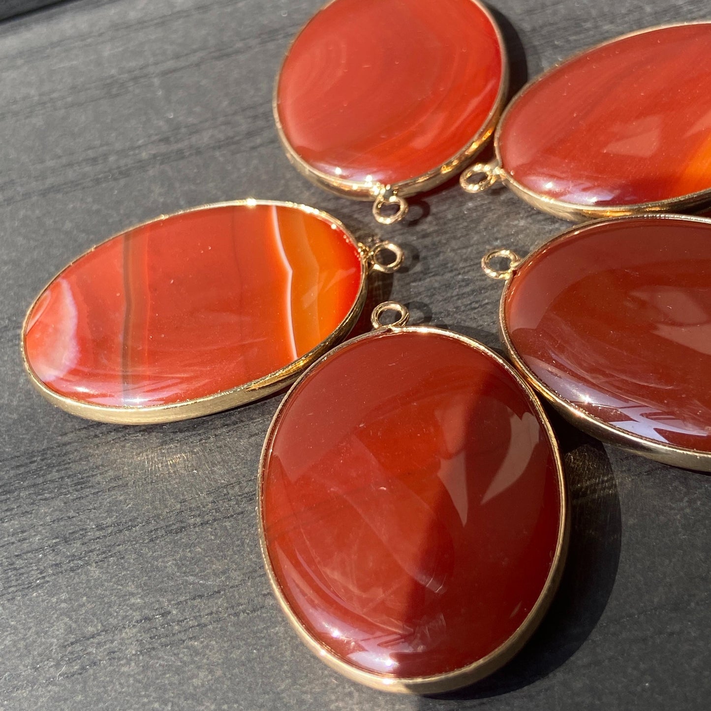 Handgeschliffener ovaler Naturstein Anhänger aus rotem Achat mit goldfarbener Fassung für DIY Schmuckherstellung und Boho Halsketten