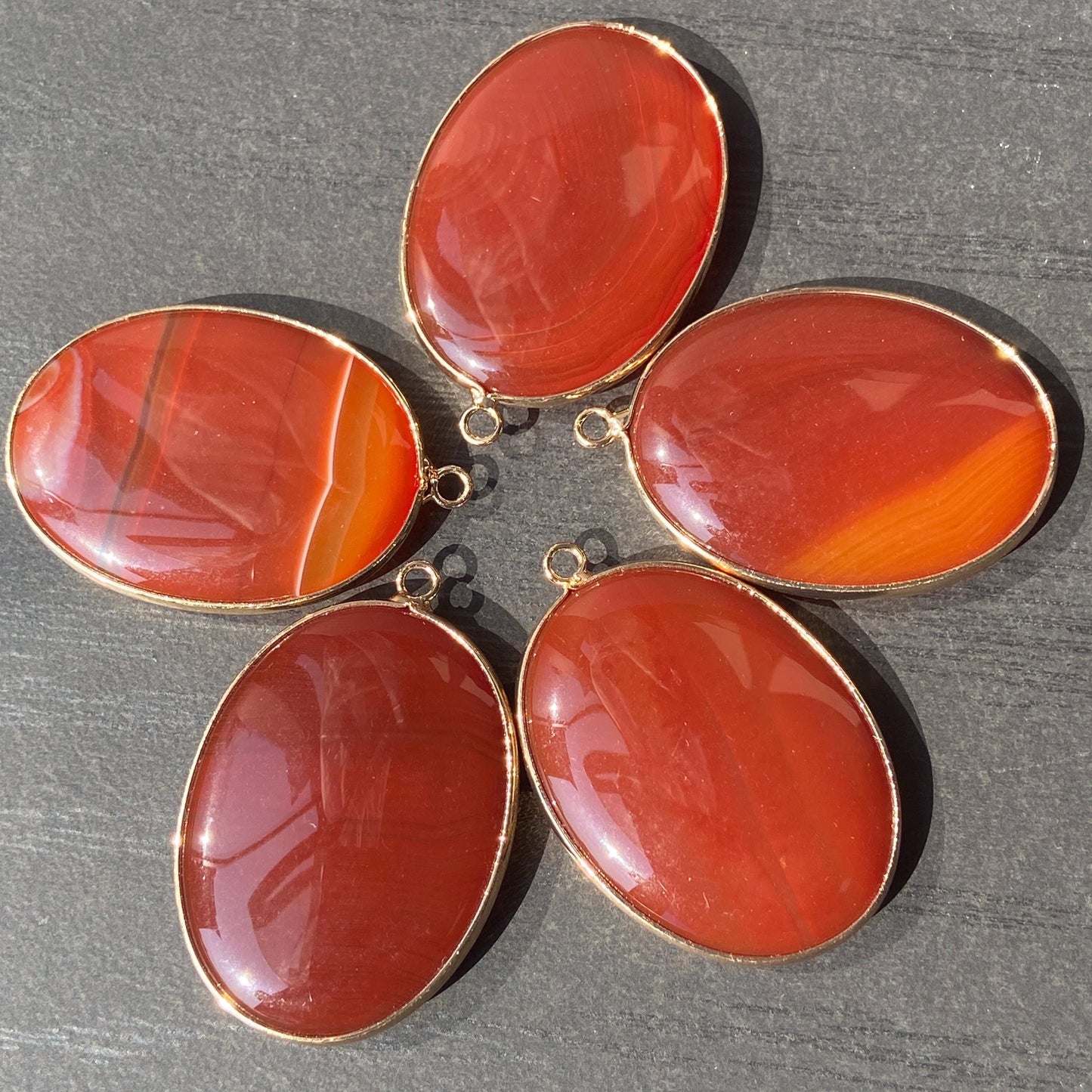 Handgeschliffener ovaler Naturstein Anhänger aus rotem Achat mit goldfarbener Fassung für DIY Schmuckherstellung und Boho Halsketten