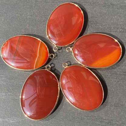 Handgeschliffener ovaler Naturstein Anhänger aus rotem Achat mit goldfarbener Fassung für DIY Schmuckherstellung und Boho Halsketten