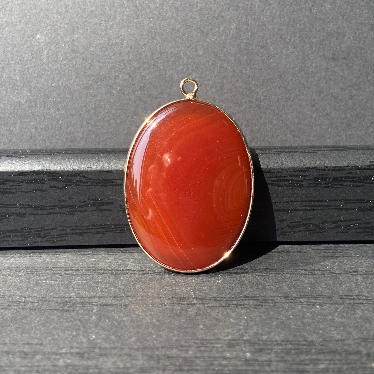 Handgeschliffener ovaler Naturstein Anhänger aus rotem Achat mit goldfarbener Fassung für DIY Schmuckherstellung und Boho Halsketten