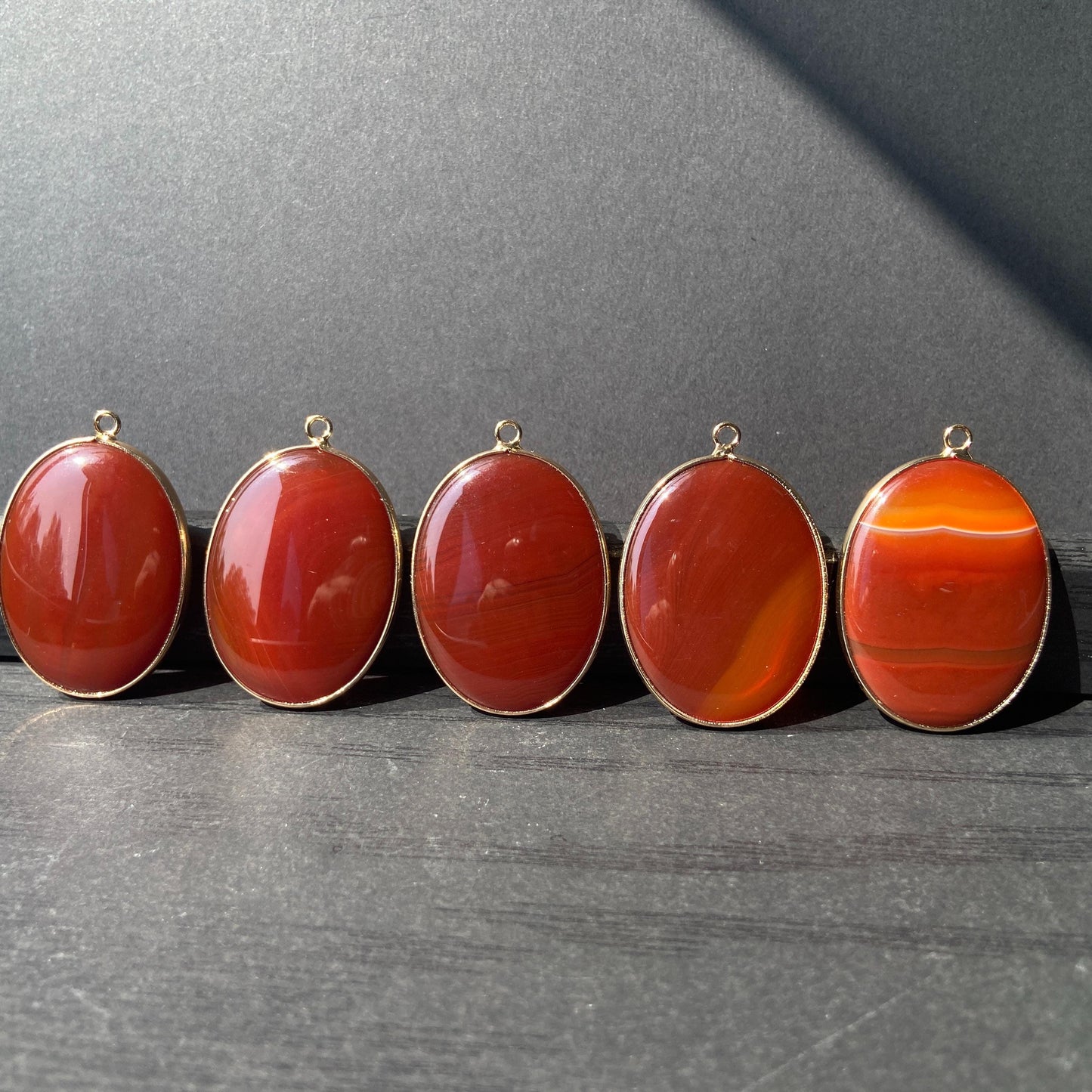 Handgeschliffener ovaler Naturstein Anhänger aus rotem Achat mit goldfarbener Fassung für DIY Schmuckherstellung und Boho Halsketten