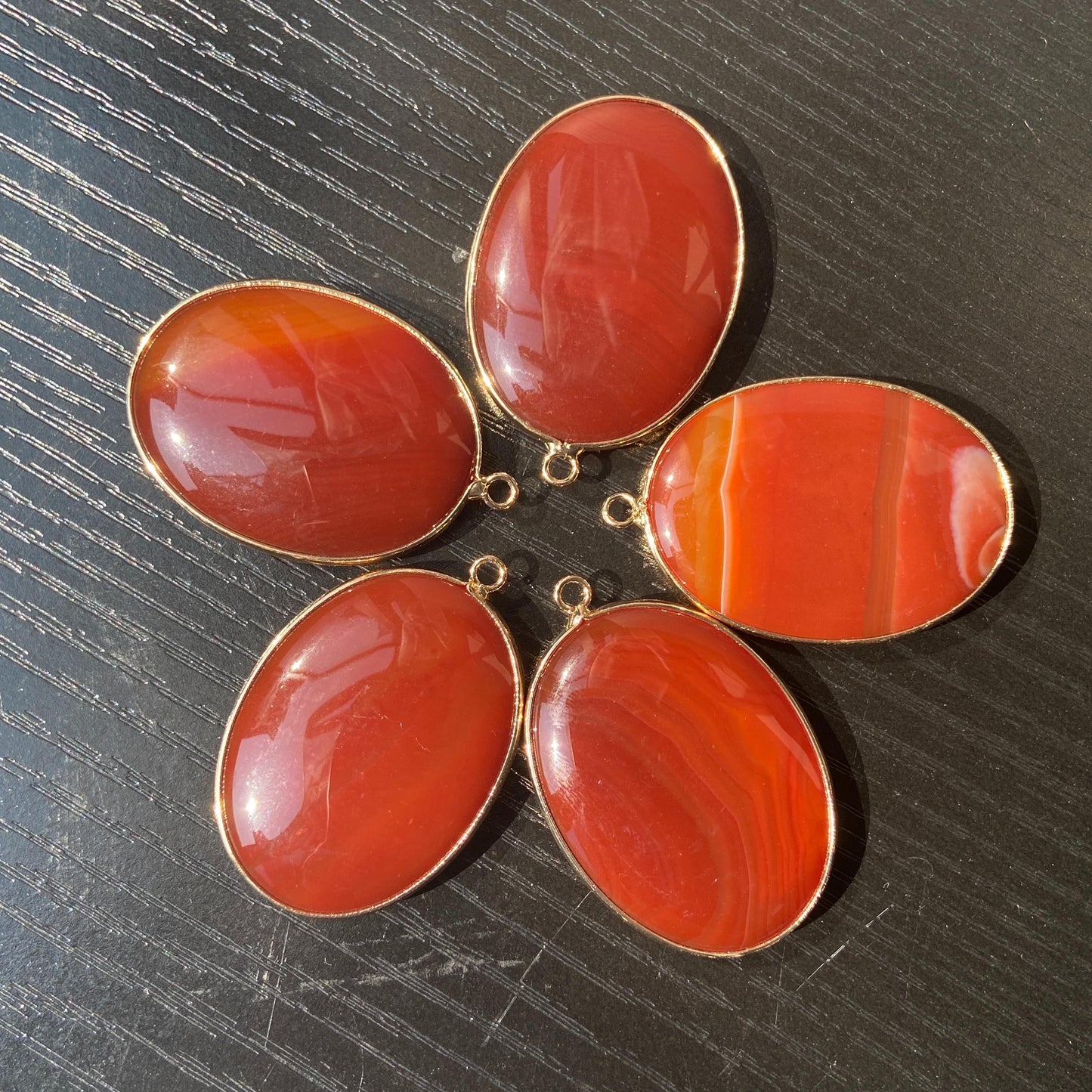 Handgeschliffener ovaler Naturstein Anhänger aus rotem Achat mit goldfarbener Fassung für DIY Schmuckherstellung und Boho Halsketten