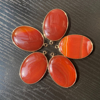 Handgeschliffener ovaler Naturstein Anhänger aus rotem Achat mit goldfarbener Fassung für DIY Schmuckherstellung und Boho Halsketten